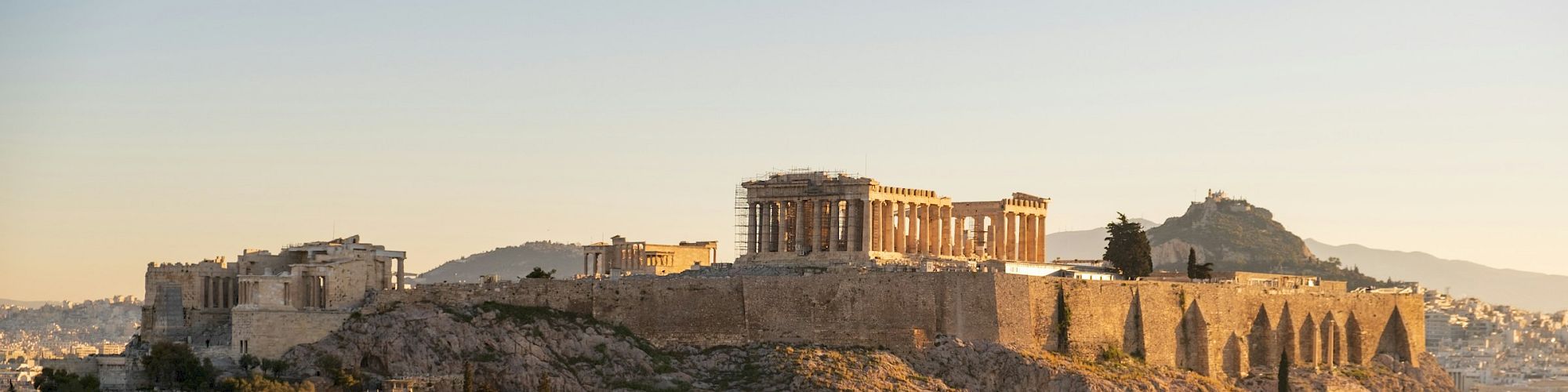 Sunset over the Acropolis of Athens, where the Parthenon rises above ancient ruins.