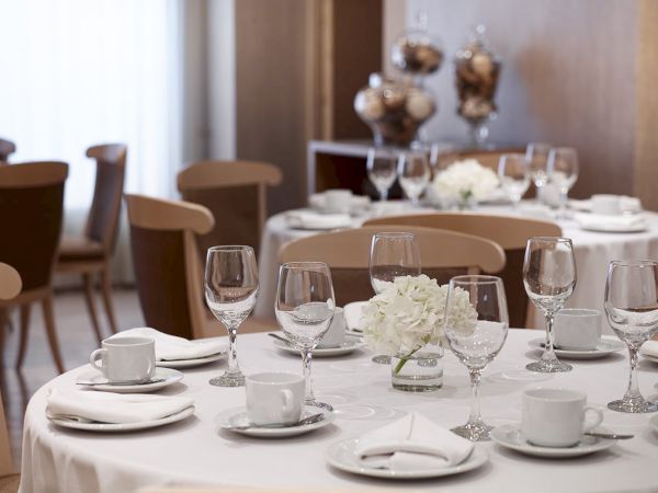 A dressed-up banquet table with white flowers, wine glasses, and cutlery, ready for a formal meal.