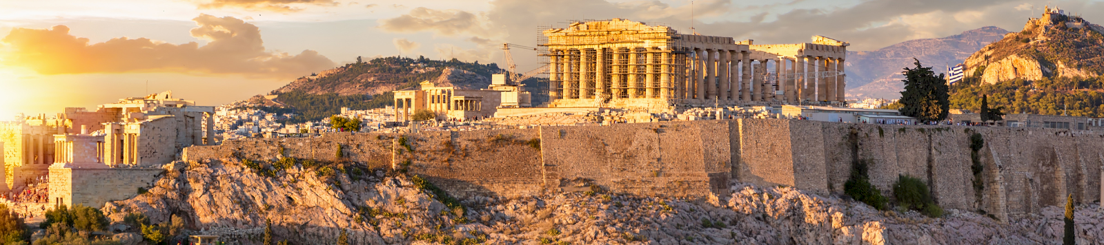 Athens’ Acropolis shines at sunset, with the Parthenon and surrounding ancient columns glowing in the golden sky.